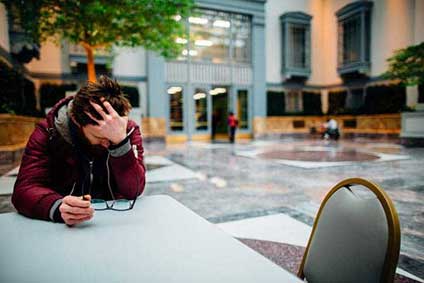 man sitting at table and hanging head because of sexual performance anxiety
